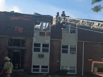 Firefighters work on the roof of the south building of Four Seasons Apartments on Warwick Avenue following a fire there early Sept. 19.