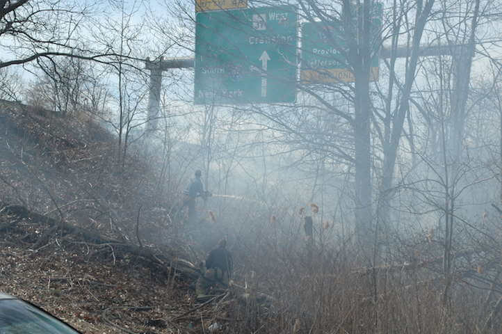 [CREDIT: Rob Borkowski] Firefighters bring a water line to bear on a brush fire on the Rte. 37 overpass on Jefferson Boulevard today at about 2:30 p.m.