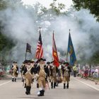 [CREDIT: Beth Hurd] Members of the Lexington Minutemen emerge from the smoke of their recently fired muskets, walking along the red, white and blue-striped Gaspee Days parade route on Saturday, June 11.