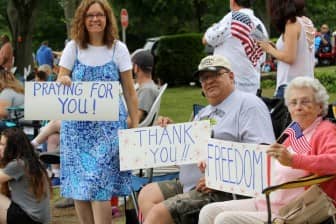 [CREDIT: Beth Hurd] Members of the Scott family - Diane and Don Scott, and Don's 88-year old mother Florence Scott, hold up signs as they cheer on their favorite civic groups.