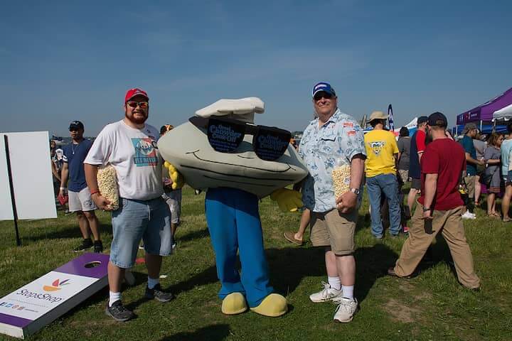 [CREDIT: Mary Carlos] From left, Bill Issler of Cranston and Eric Hudson of Providence pose with the Chowder Cook-Off Clam during the Great Chowder Cook-Off at Fort Adams, Newport.