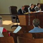 [CREDIT: Rob Borkowski] School Committee Chair Karen Bachus consults with fellow School Committee person Judy Cobden. School Committee member Nathan Cornell is seated in front of them.