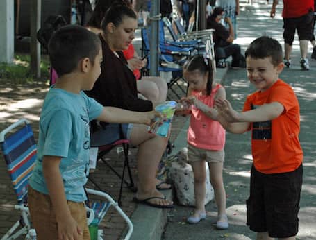 [CREDIT: Rob Borkowski] From left, Giani Rodis, 6, watching with his grandmother, Faye Mitchell of Warwick blows bubbles at Mathew Gilmore, 4. while waiting for the 2019 Gaspee Days Parade Saturday, June 8.