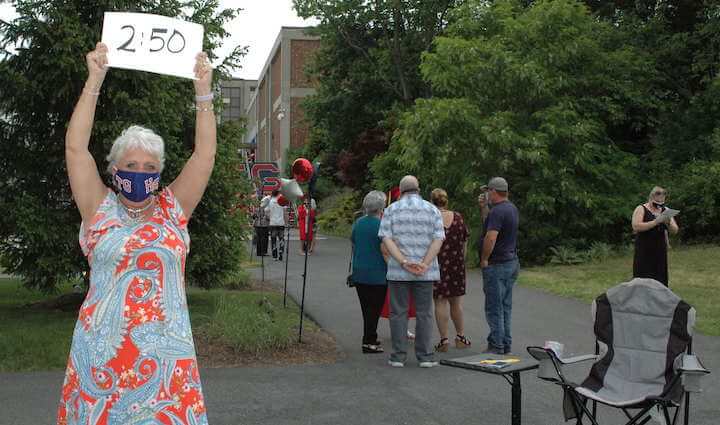 [CREDIT: Rob Borkowski] Tollgate secretary Toni Anderson holds a sign letting the next group of graduates know their appointment is up.