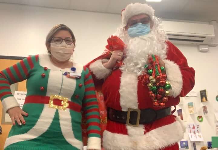 [CREDIT: CNE] Dick Oakley (Santa/pharmacist) and Cindy Santana (Elf/Pharmacy technician) visited the COVID-19 Field Hospital in Cranston to hand out gifts bags filled with get well/holiday cards, crossword puzzles, and decks of playing cards donated from the community.