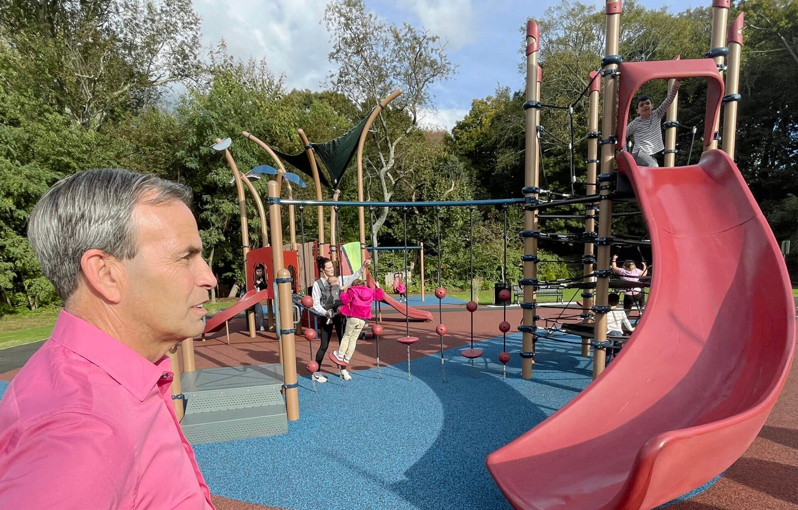 [CREDIT: Rob Borkowski] Mayor Frank Picozzi, left, and his grandson, right, top of slide, at the new Apponaug Playground Tuesday for the ribbon cutting ceremony.