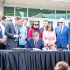 [CREDIT: RI Legislative Press and Information Bureau] Legislative leaders join Gov. Dan McKee for a ceremonial signing of legislation creating the Hope Scholarship Wednesday at Rhode Island College.