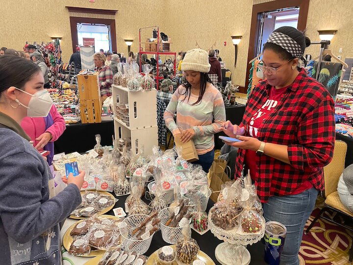 [CREDIT: Rob Borkowski] Carissa Meekins, owner of Divas Dips and Gourmet Treats of Pawtucket, right, and Brielle Samson package up treats for customers at Shop RI Nov. 25, 2023.