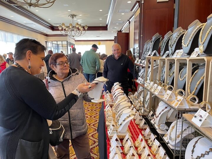 [CREDIT: Rob Borkowski] From left, Robyn Golden, owner of R. Golden Designs jewelry, and designer of said jewelry, reviews a piece with Maureen Lilla. Golden's husband, Jeffrey, looks on. 