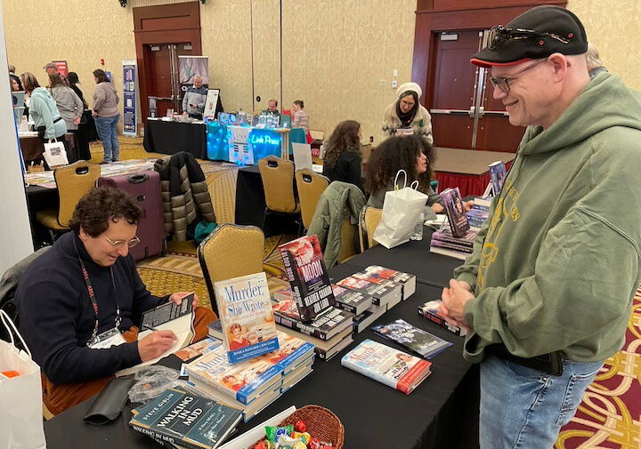 [CREDIT: Rob Borkowski] Best-selling thriller novelist and Rhode Islander Jon Land signs a copy of his latest novel for Joel Gluck of Warwick during the RI Author Expo at Crowne Plaza Warwick Saturday.