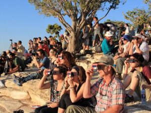 [CREDIT: National Park Service] A crowd uses handheld solar viewers and solar eclipse glasses to safely view a solar eclipse.