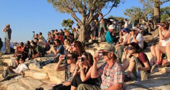 [CREDIT: National Park Service] A crowd uses handheld solar viewers and solar eclipse glasses to safely view a solar eclipse.