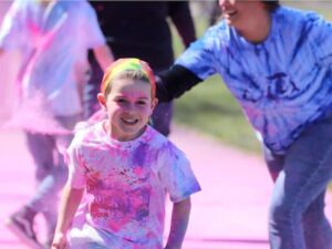 [CREDIT: Roberta Canestrari] First-grader (now second grader) Conor Gill runs during the 2023 Warwick Neck Color-a-thon. Second grade teacher Kirstin Silvia is visible behind him.