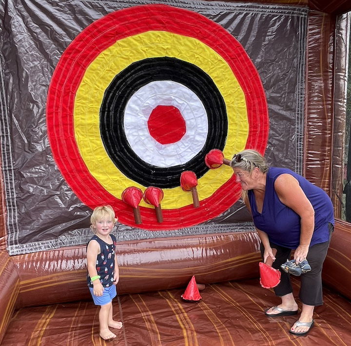 [CREDIT: Rob Borkowski] Cathy Cudoni supervised her grandson, Lincoln, 2, in some inflatable axe-throwing courtesy of Bing's Backyard Bash during Granparent's Day at the Coventry Town Annex Saturday.