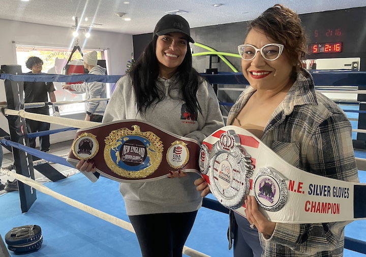 [CREDIT: Rob Borkowski] From left, Jessica Emery and Abraham Ceron's mom, Zolina Medina, with silver gloves belts won by students. In the background, boxing gym coach Miguel Cruz and Medina's son, Abraham Ceron, discuss their sparring match at the Hard Knocks grand opening Saturday, Nov. 23.