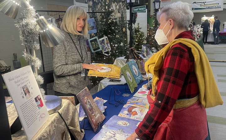 [CREDIT: Rob Borkowski] Illustrator Joan Klatil Craemer, one of the organizers of the Three Ladies Craft show, talks about her children's books for sale with fellow illustrator Terry Kole during the art show. 