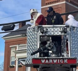 [CREDIT: Rob Borkowski] Santa and Mrs. Claus are delivered to the front lawn of Warwick Central Baptist Church by WFD ladder truck during the Rolling, Strolling Apponaug Winter Festival Dec. 7, 2024.