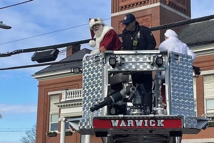 [CREDIT: Rob Borkowski] Santa and Mrs. Claus are delivered to the front lawn of Warwick Central Baptist Church by WFD ladder truck during the Rolling, Strolling Apponaug Winter Festival Dec. 7, 2024.