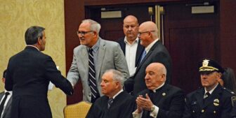 [CREDIT: Rob Borkowski] Mayor Frank Picozzi shakes hands with re-elected School Committee Member David Testa, followed by newly elected School Committee Member Sean Wiggins, at Crowne Plaza Jan. 7, 2025.